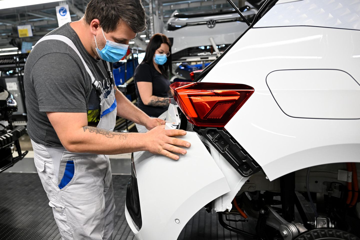 Mitarbeitende montieren die Heckpartie eines Autos im VW Werk Zwickau