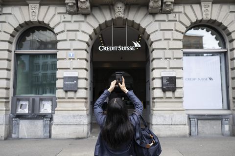 Eine Frau fotografiert mit ihrem Smartphone den Eingang zur Credit Suisse