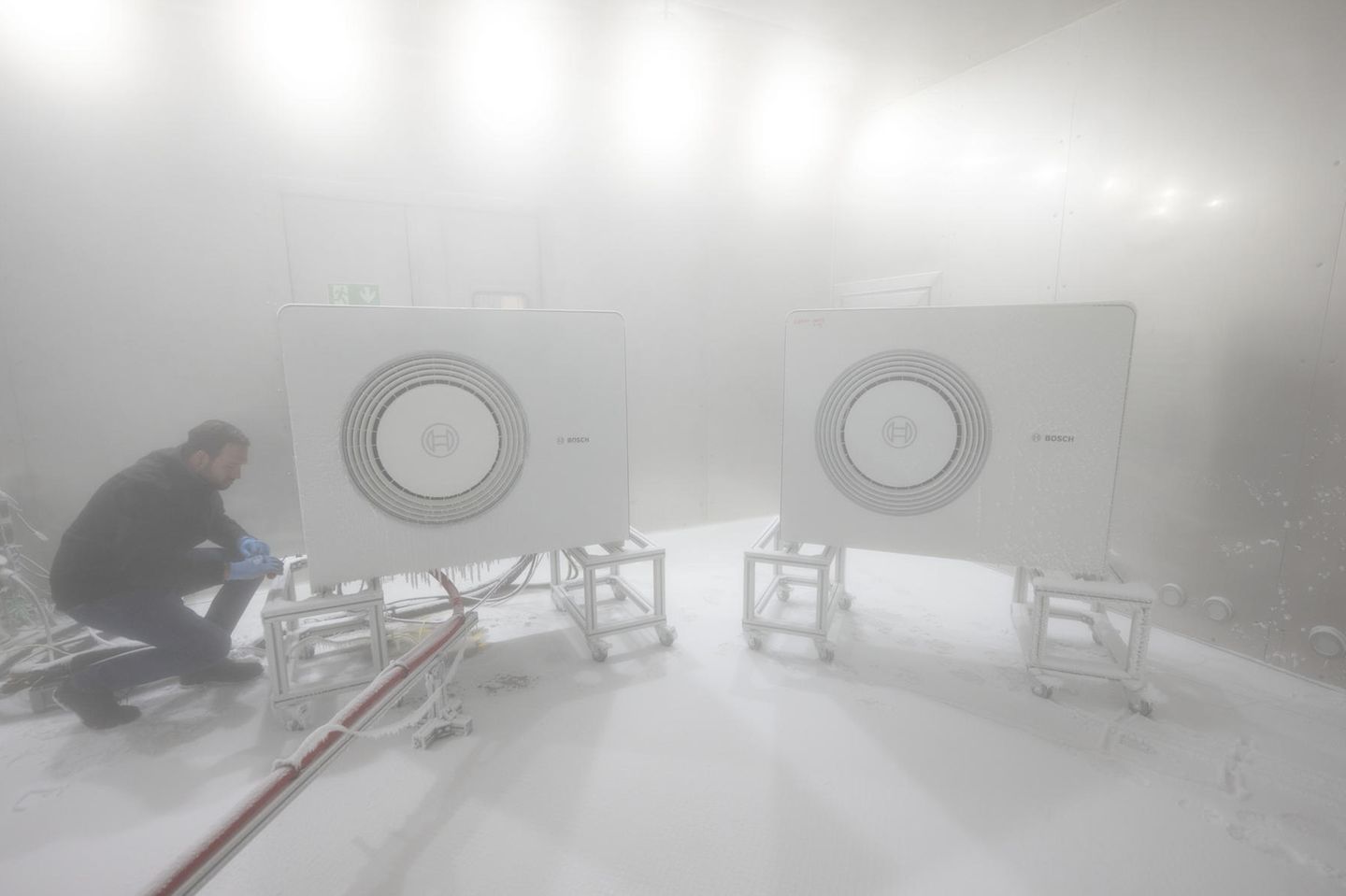 Ein Bosch-Mitarbeiter öffnet in einer Klimakammer das Gehäuse einer Wärmepumpe