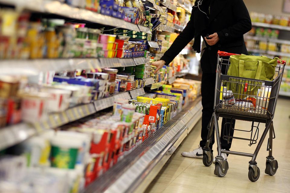 Ein Kunde mit Einkaufswagen neben einem Supermarktregal Inflation