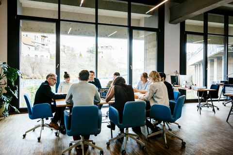 Frauen und Männer sitzen im Büro um einen Konferenztisch herum
