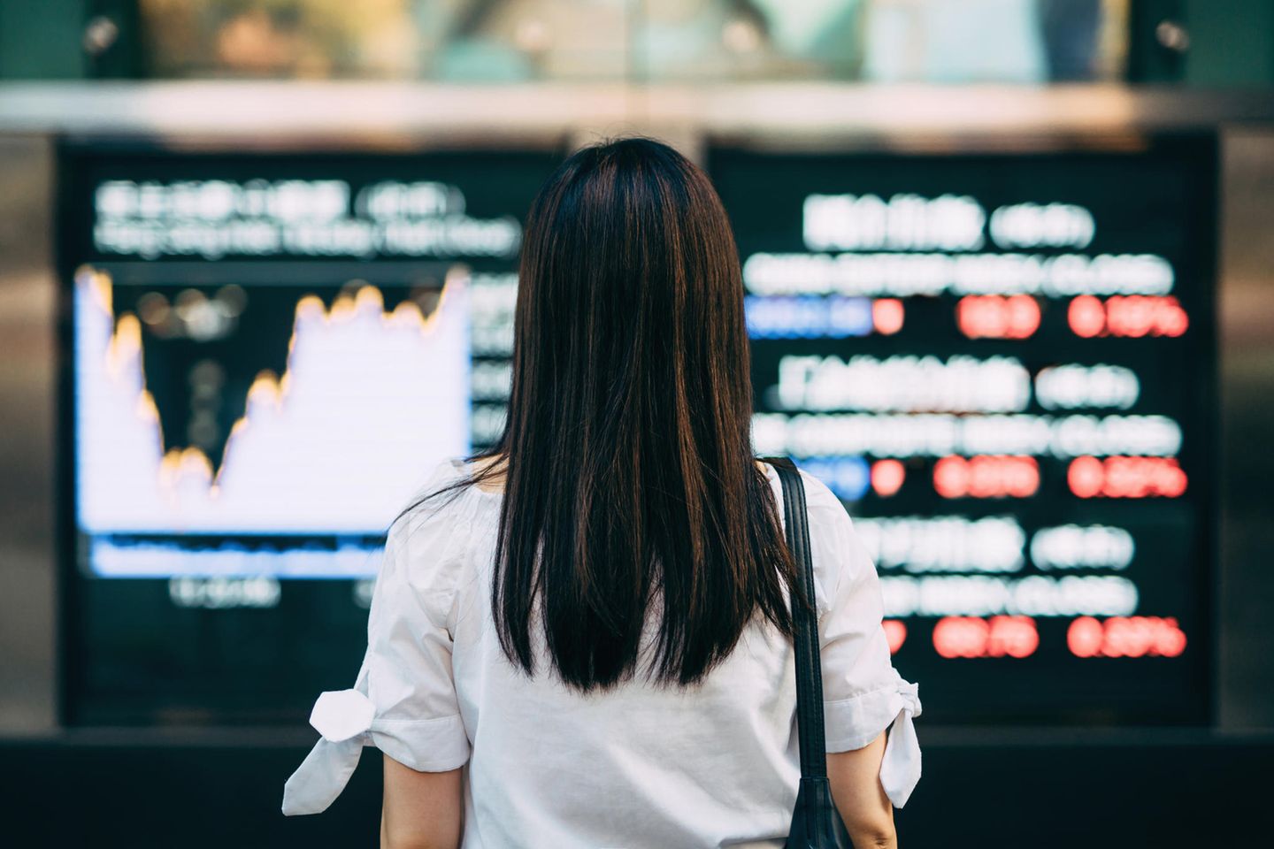 Ein Frau blickt auf einen Bildschirm mit Finanzmarktinformationen