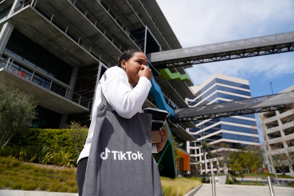 Eine Frau mit einer Tiktok-Tasche steht vor der US-Zentrale des Unternehmens