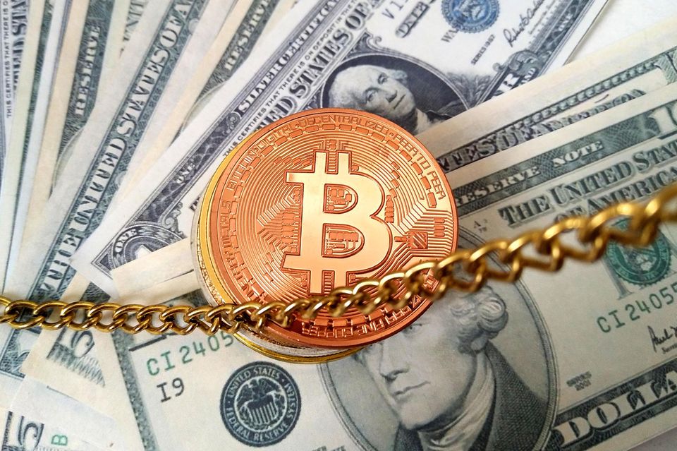 Eine Bitcoin-Münze liegt auf Dollar-Scheinen