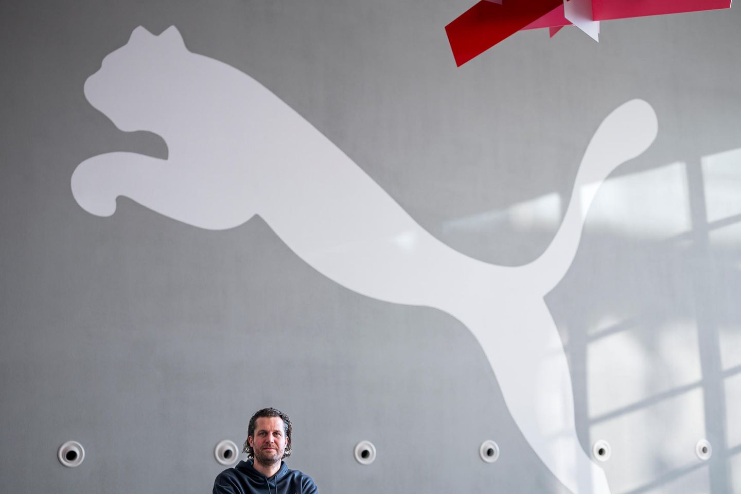Puma-CEO Arne Freundt steht vor dem Logo des Konzerns