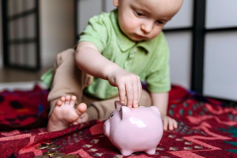 Ein Kleinkind steckt ein Geldstück in ein Sparschwein