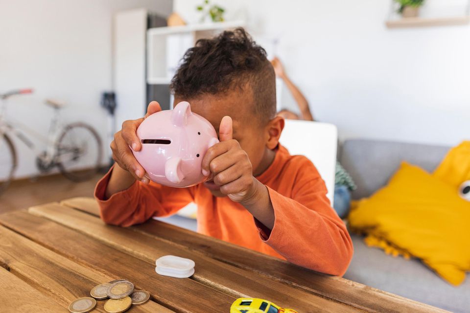 Ein Junge leert ein Sparschwein, um das Geld darin zu zählen