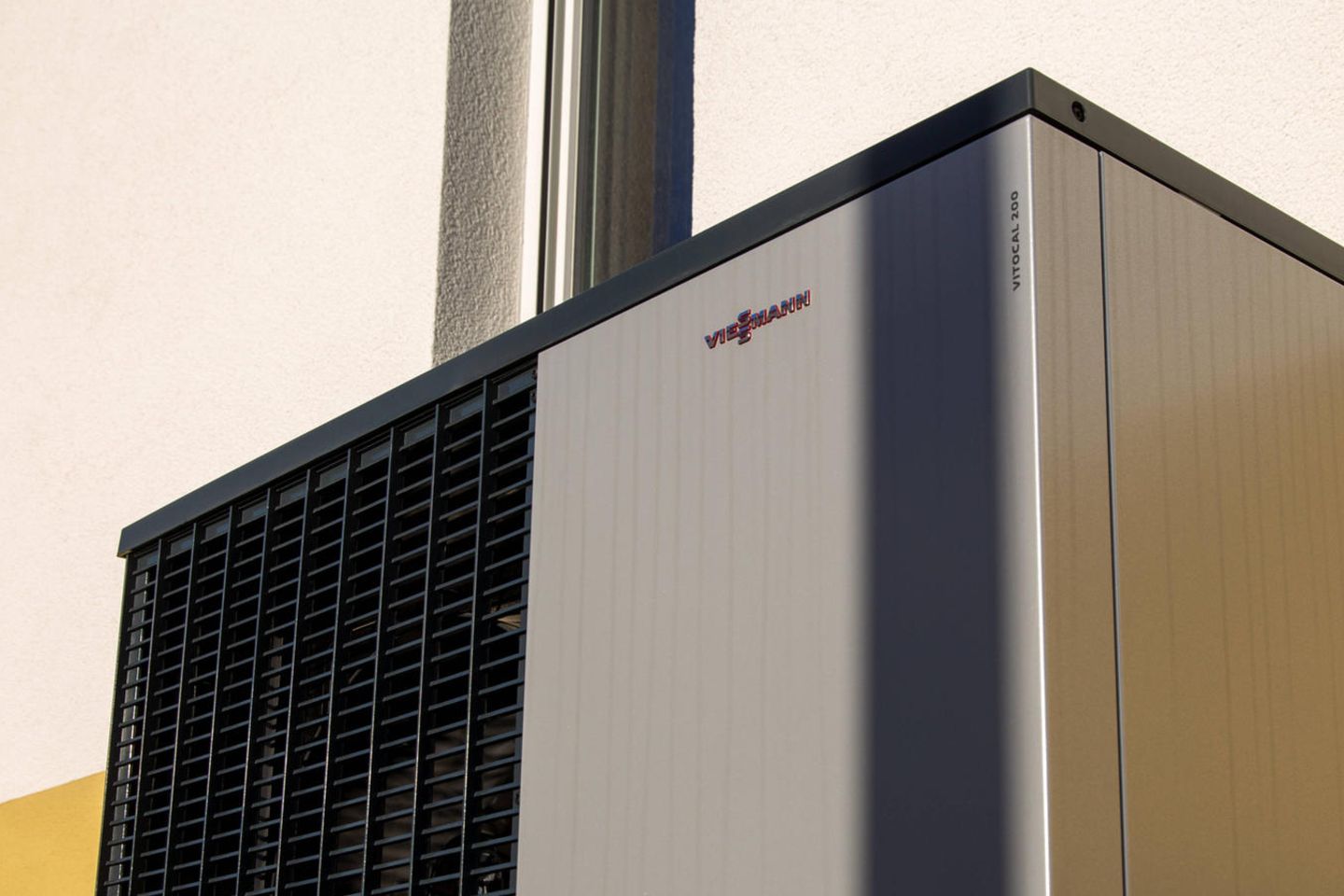Eine Luft- und Wasserwärmepumpe von Viessmann steht an einem Wohnhaus