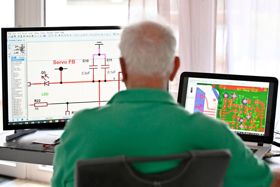 Ein Senior arbeitet in seiner Elektronik-Werkstatt im Homeoffice an seinem Computer