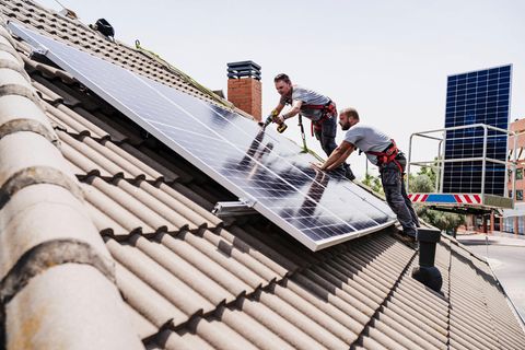 Handwerker installieren Solarpanele auf einem Hausdach