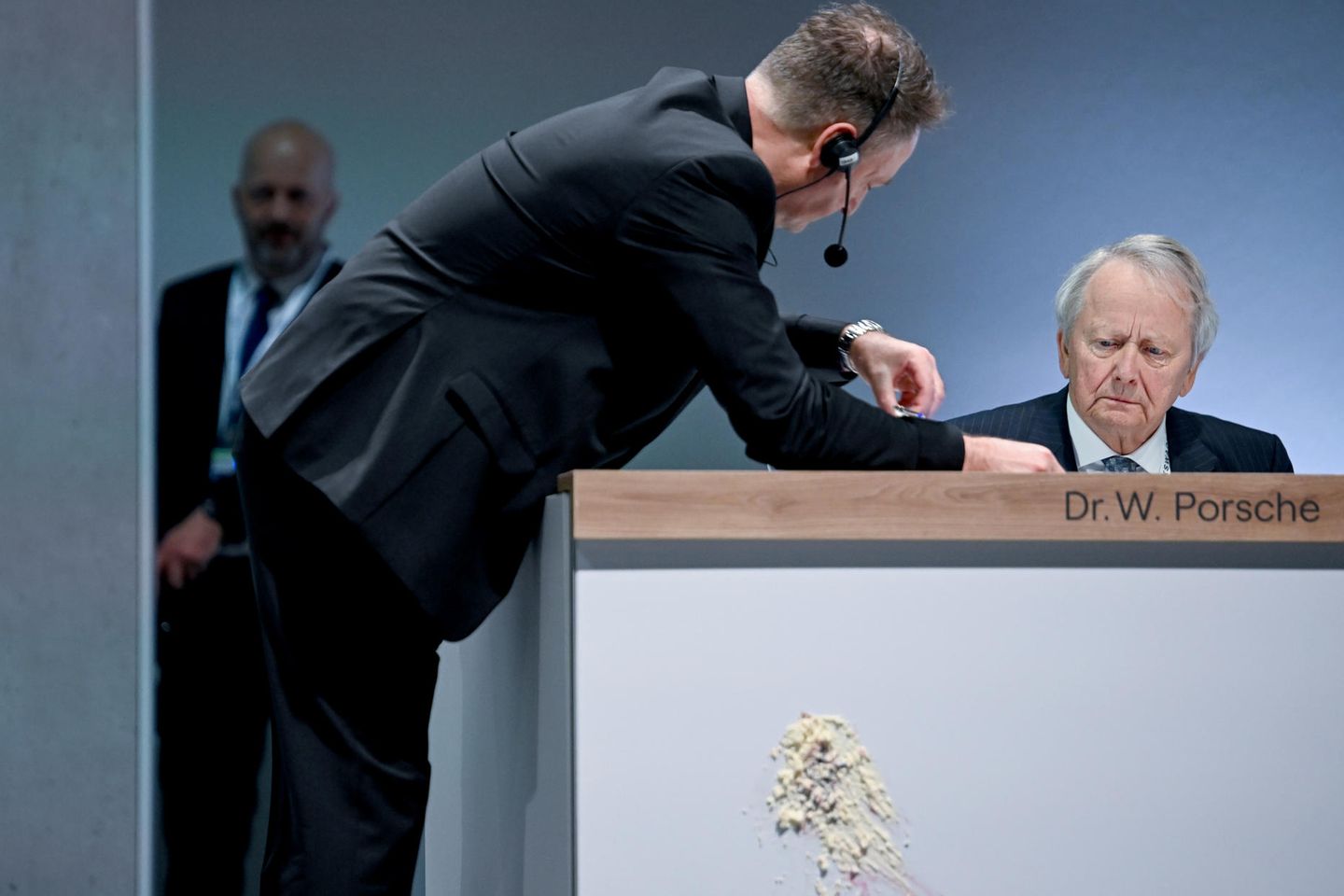 Wolfgang Porsche sitzt auf dem Podium, an dem man einen Abdruck nach einem Tortenwurf sieht