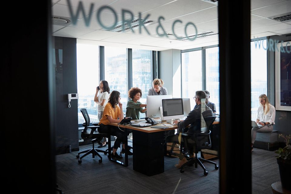Mtarbeiterinnen und Mitarbeiter diskutieren in einem Büro