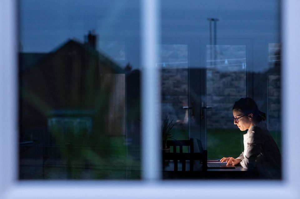 Eine Frau arbeitet in der Dunkelheit an ihrem Rechner