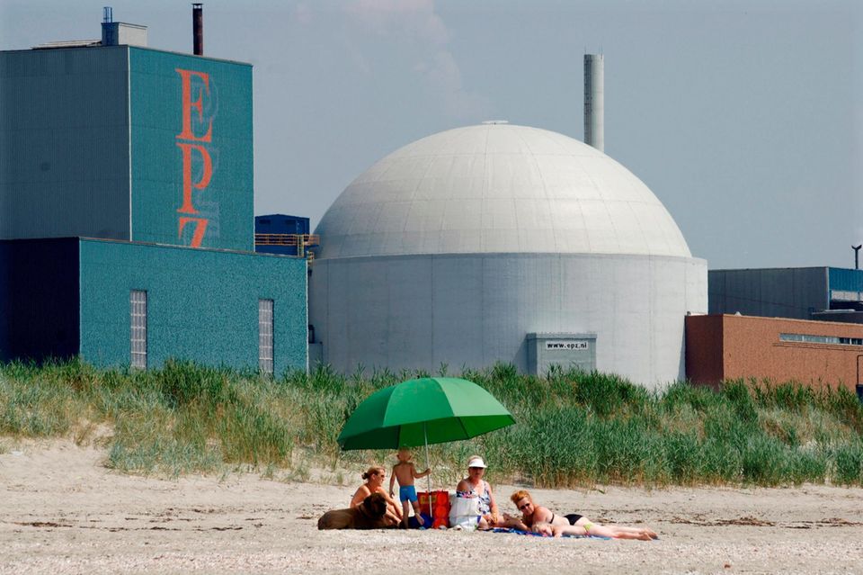 Drei Frauen mit Kindern und einem Hund liegen am Strand vor dem Atomkraftwerk Borssele