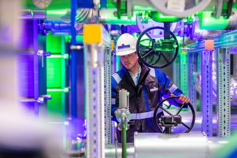 Ein Mitarbeiter der Stadtwerke steht in der mit farbigem Licht illuminierten Geothermieanlage der Stadtwerke Schwerin