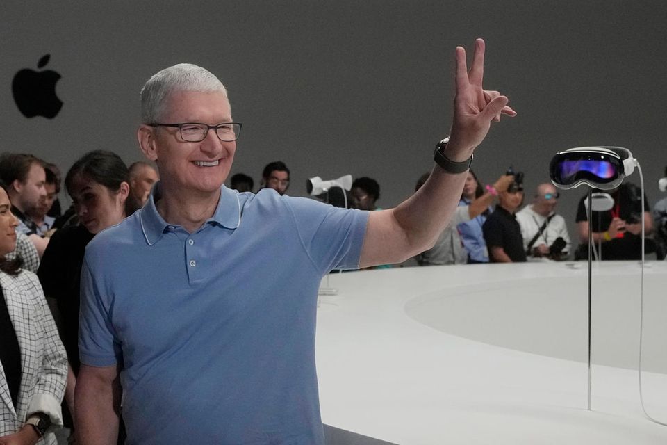 Tim Cook, CEO von Apple, steht neben den neuen Apple Vision Pro Headsets in einem Ausstellungsraum