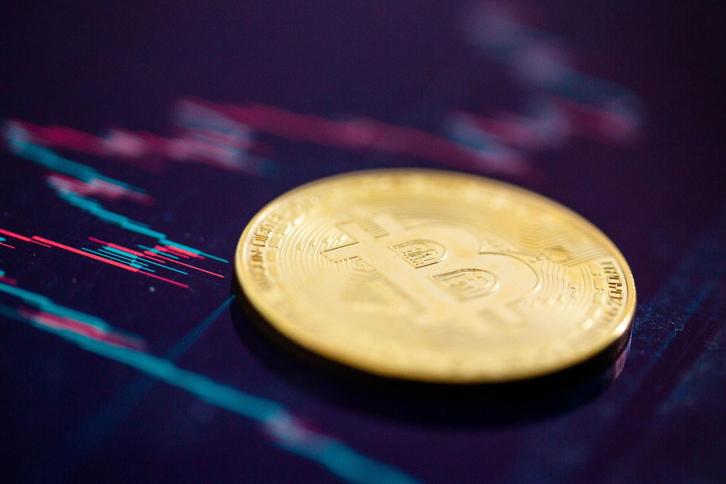 Eine Bitcoin-Münze liegt auf einem Bildschirm, der den Bitcoin-US-Dollar Kurs zeigt