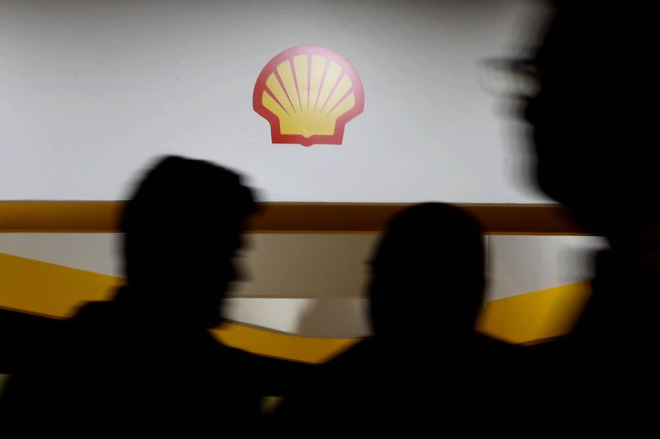 Menschen gehen auf einer Konferenz an einem Shell-Logo vorbei