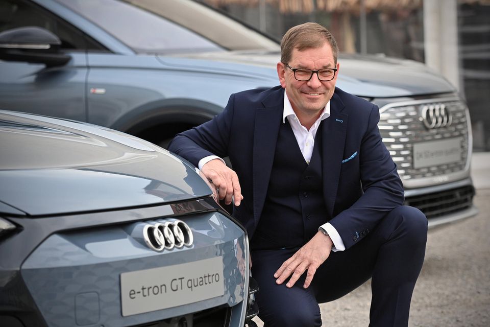 Markus Duesmann posiert an der Front eines Audi e-tron gt quattro