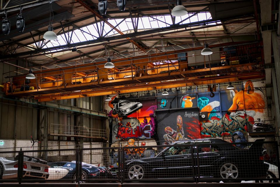 Autos in einer alten Industriehalle mit Graffitis