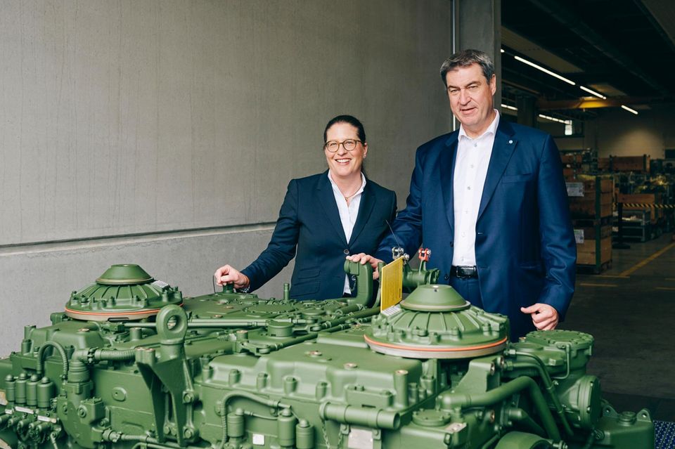 Susanne Wiegand und der bayerische Ministerpräsident Markus Söder hinter dem Getriebe eines Kampfpanzers. Der Wind hat sich gedreht, Rüstung ist kein Tabuthema mehr