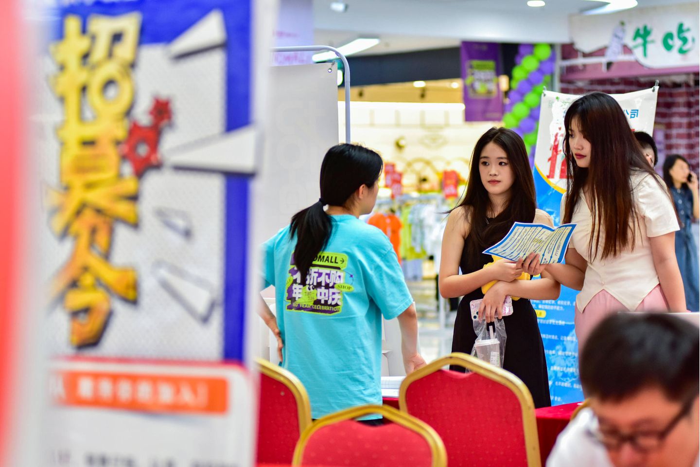Zwei junge Chinesinnen lassen sich auf einer Jobmesse in China beraten