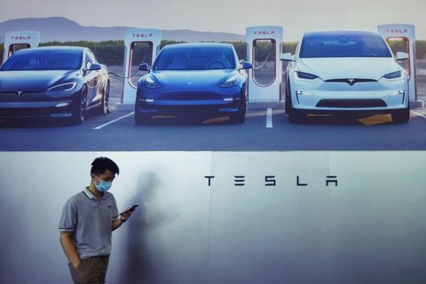 Ein maskierter Mann geht am Stand von Tesla auf der Weltkonferenz für künstliche Intelligenz in Schanghai vorbei