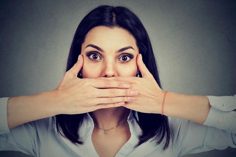 Eine Frau hält sich die Hände vor den Mund