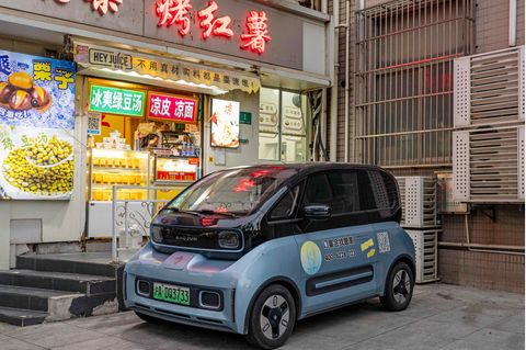Ein kleines E-Auto steht vor einem Imbiss in Schanghai