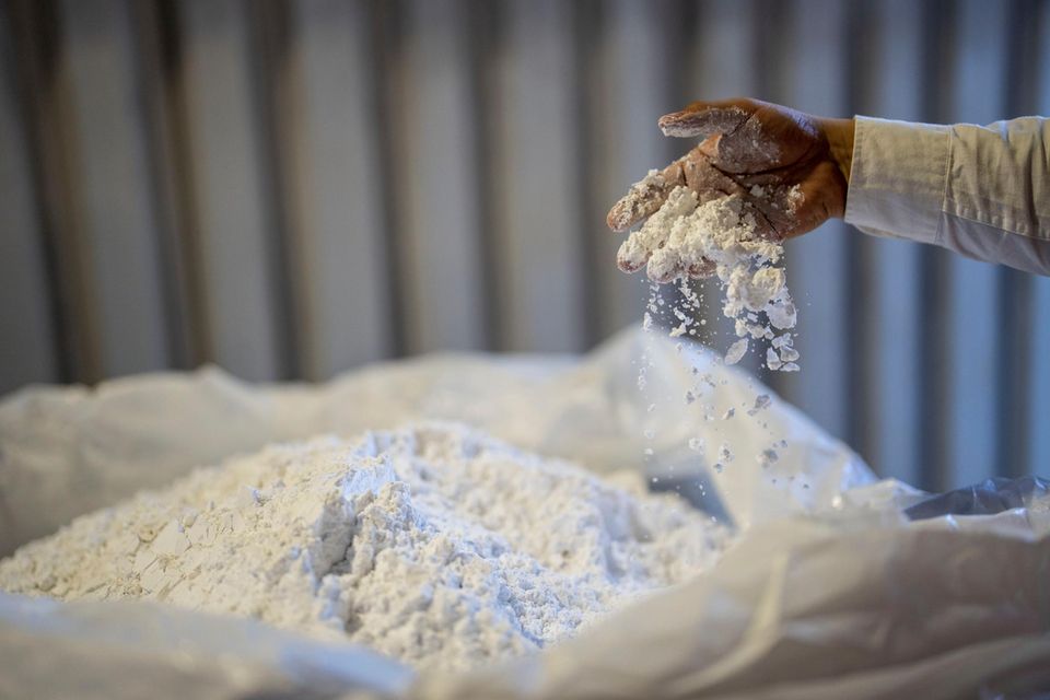 Ein Arbeiter rührt mit seiner Hand in einem Sack mit Lithium
