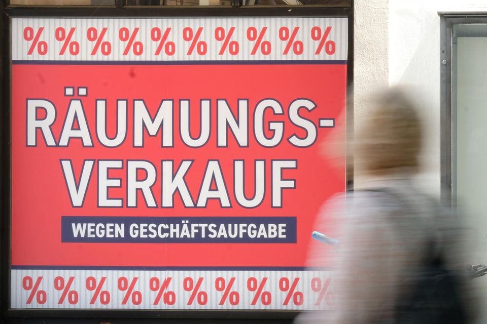 Zwei Frauen gehen an einem Geschäft vorbei an dem „Räumungsverkauf wegen Geschäftsaufgabe“ steht