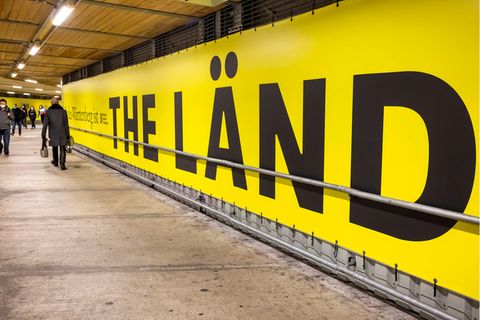 „The Länd" steht auf einem Werbebanner im Hauptbahnhof Stuttgart