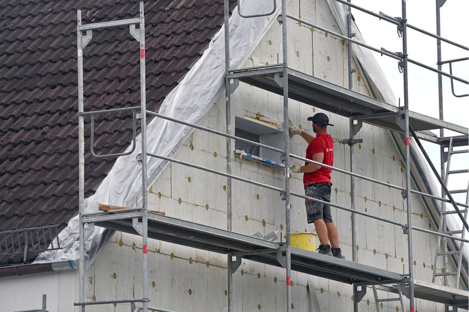 Handwerker steht auf einem Baugerüst an einem Haus