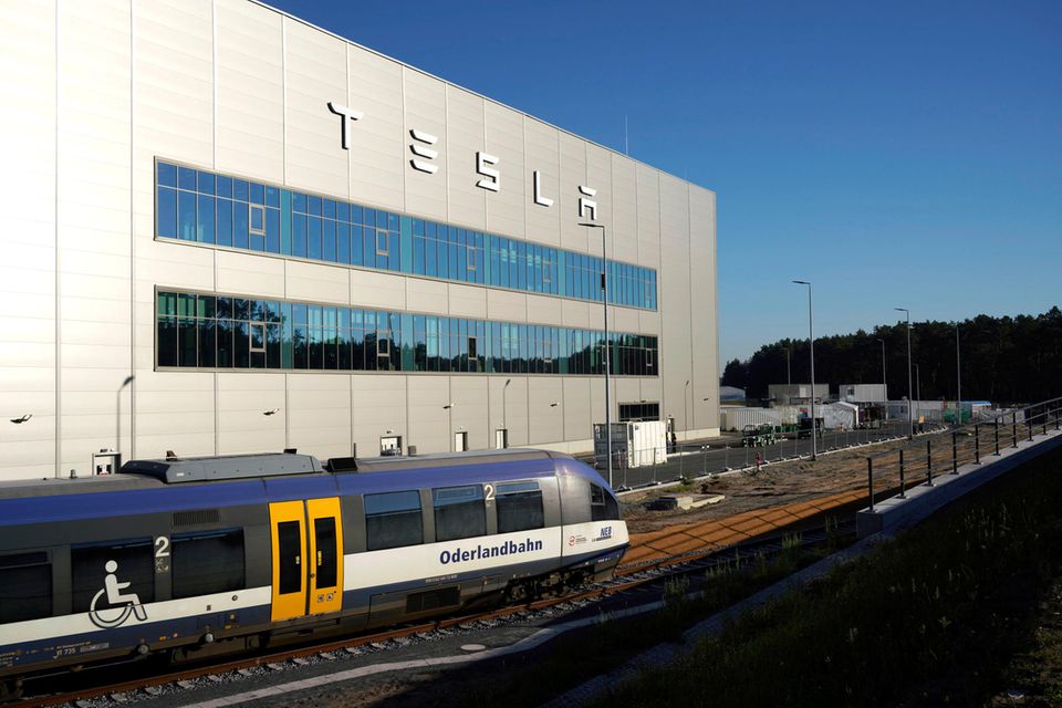 Eine Eisenbahn fährt am Tesla-Werk in Grünheide vorbei