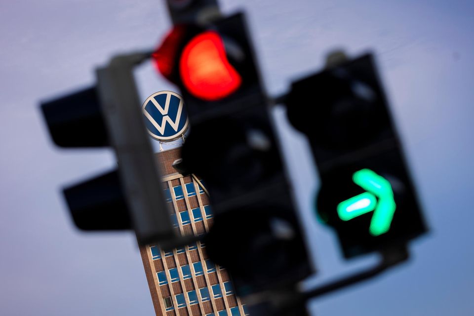 Das Markenhochhaus im Volkswagen Stammwerk ist am Morgen hinter einer Ampel zu sehen