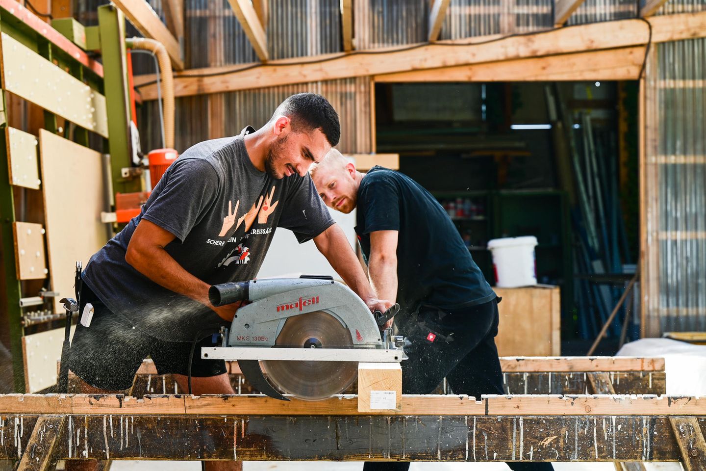 Shariar Nikbakht sägt Holz mit Moritz Wierzba