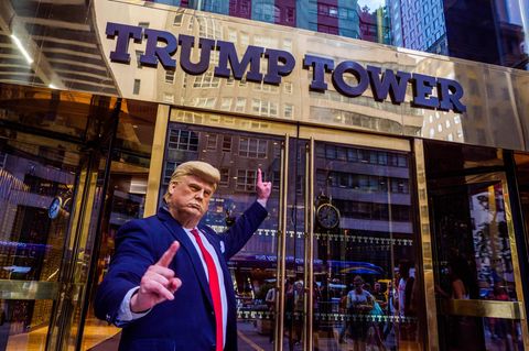Trump-Darsteller zeigt auf ein Schild mit der Aufschrift „Trump Tower“