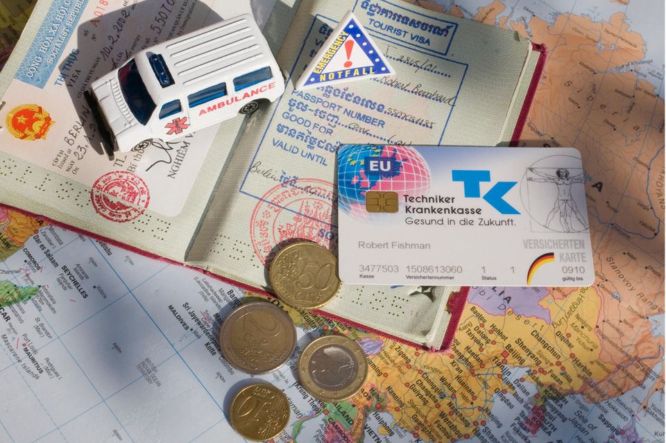 Pass, Geldmünzen und eine Krankenkassenkarte liegen auf einer Landkarte