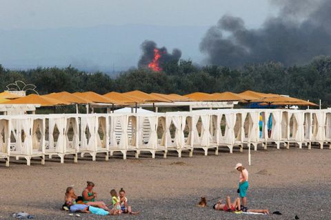 Touristen auf der russisch besetzten Krim – dahinter brennt ein Militärstützpunkt
