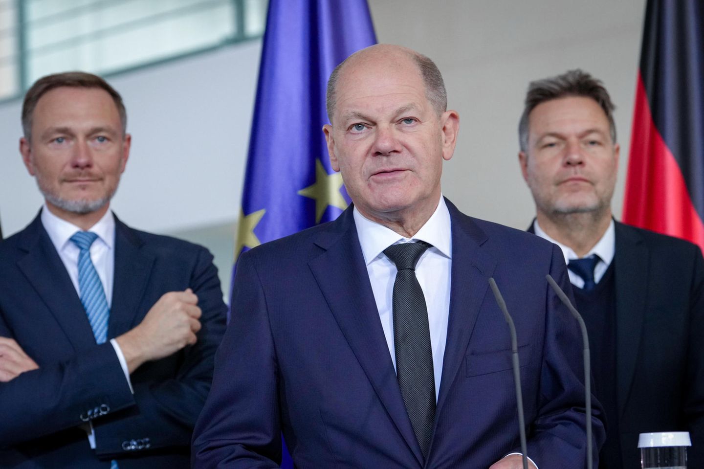 Kanzler Scholz spricht, Finanzminister Lindner und Wirtschaftsminister Habeck stehen im Hintergrund
