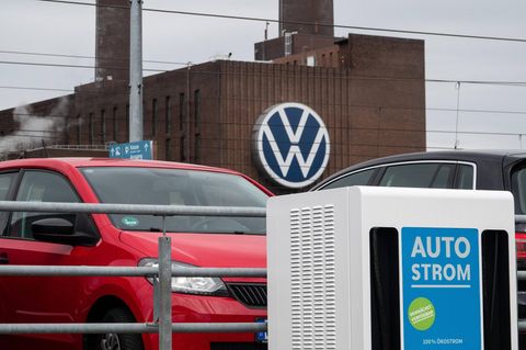 Eine Ladestation für Elektrofahrzeuge steht auf einem Parkplatz, im Hintergrund ist das Volkswagen Werk
