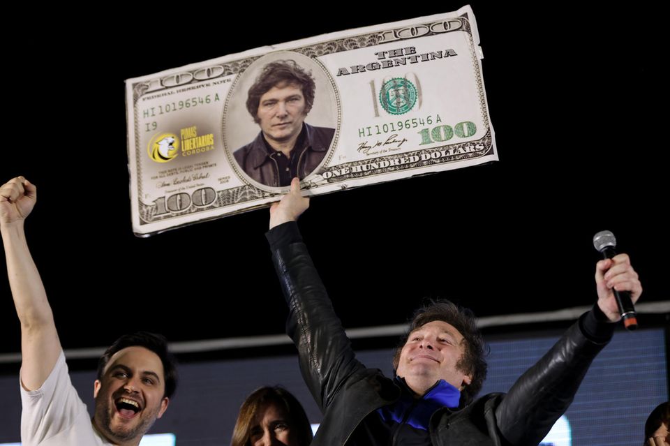 Javier Milei reckt im Wahlkampf ein Plakat, auf dem eine Dollar-Note mit seinem Konterfei zu sehen ist, in die Höhe