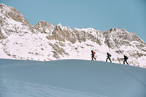 Drei Wanderer in einer schneebedeckten Berglandschaft