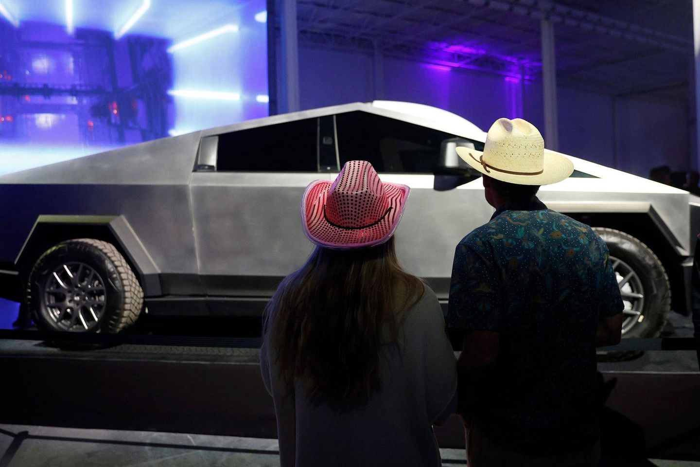 Eine Frau und ein Mann mit Cowboyhüten schauen sich einen Cybertruck an
