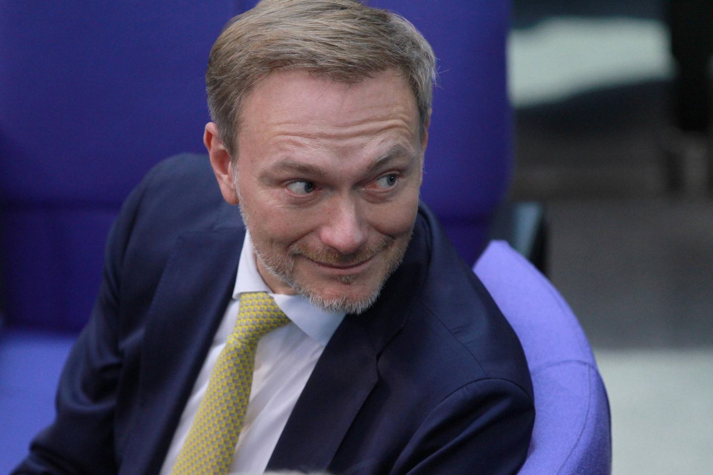 Finanzminister Christian Lindner, ein Mann mit Krawatte und Anzug, dreht sich auf einem Stuhl um