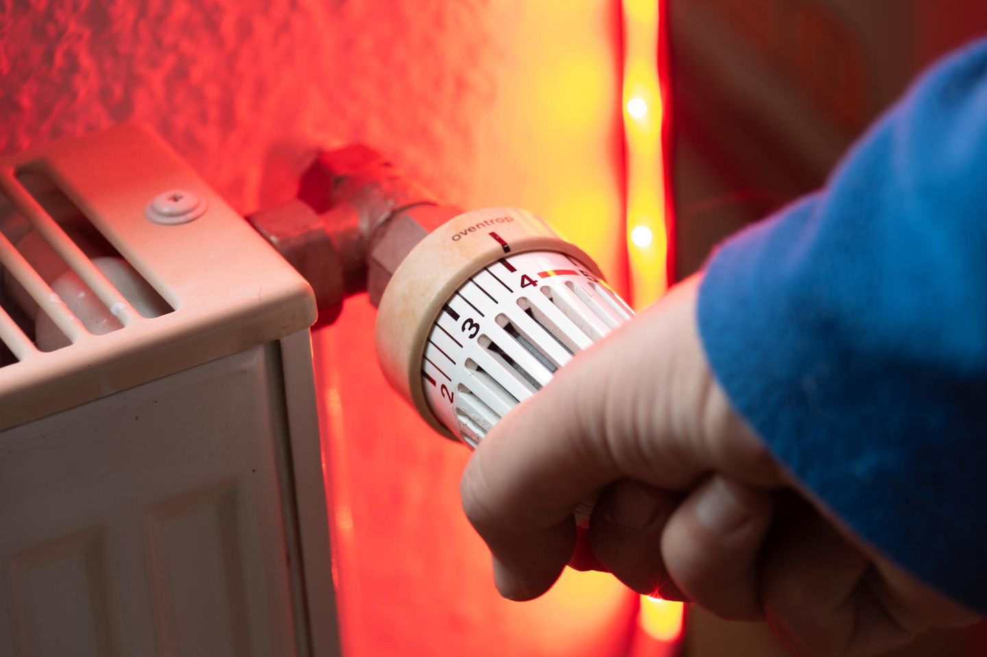 Eine Person dreht an einem Heizthermostat