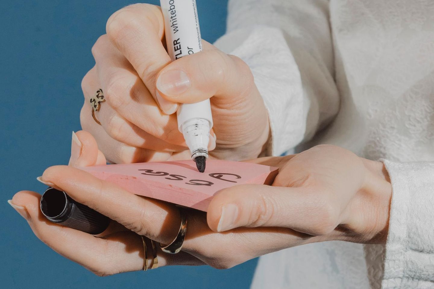Eine Frau schreibt mit einem dicken Filzstift auf einen Post-it