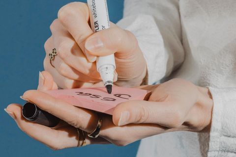 Eine Frau schreibt mit einem dicken Filzstift auf einen Post-it