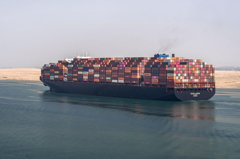 Mit bunten Containern beladenes Schiff fährt den Suezkanal entlang