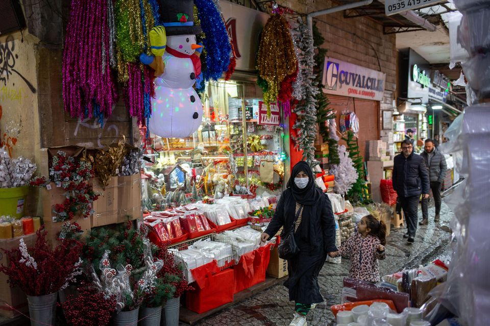 Eine Frau geht mit einem Kind an der Hand an einem Geschäft in Istanbul vorbei